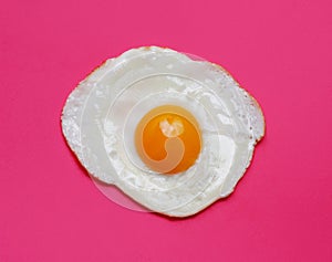 Fried egg yolk isolated on pink background