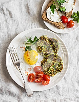 Fried egg, zucchini fritters and cream cheese sandwich - delicious breakfast, brunch or snack. On a light background