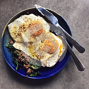 Fried eggs atop of sautÃ©ed kale and onions: homemade breakfast