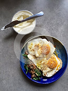 Fried eggs atop of sautÃ©ed kale and onions: homemade breakfast