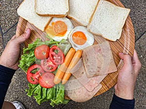 Fried eggs with bacon and grain bread on Wooden plate A man is having Breakfast. Bright yellow background. Eggs for Breakfast,