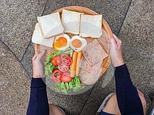 Fried eggs with bacon and grain bread on Wooden plate A man is having Breakfast. Bright yellow background. Eggs for Breakfast,