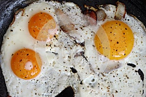 Fried eggs with bacon on the pan - hearty breakfast