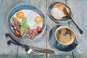 Fried eggs,  bacon, tomato, toast and a cup of coffee