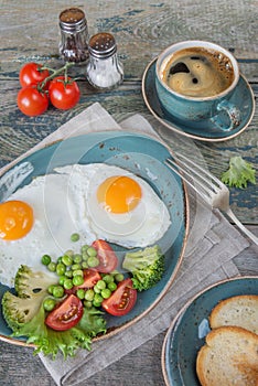 Fried eggs,  bacon, tomato, toast and a cup of coffee