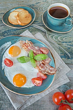 Fried eggs, bacon, tomato, toast and a cup of coffee