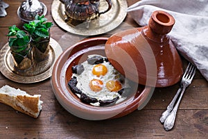 Fried eggs and beef in tajine dish with cover, Moroccan breakfast