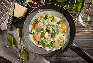 Fried eggs with broccoli, spinach, spices and cheese in a pan on a dark wooden background, Breakfast