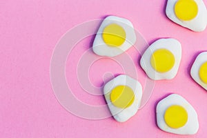 Fried eggs candy sweets on pink background with copy space