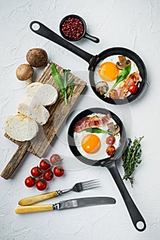 Fried eggs with cherry tomatoe and bread for breakfast in cast iron frying pan  on white background  top view flat lay