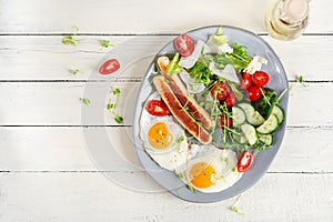 Fried eggs and chicken sausage and fresh salad. Top view, flat lay