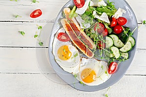 Fried eggs and chicken sausage and fresh salad. Top view, flat lay