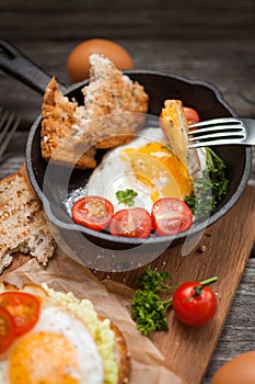 Fried eggs and fresh bread with cherry tomatoes, herbs and spices for breakfast