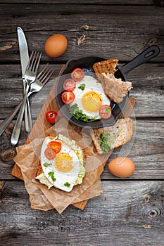 Fried eggs and fresh bread with cherry tomatoes, herbs and spices for breakfast