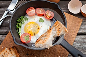 Fried eggs and fresh bread with cherry tomatoes, herbs and spices for breakfast