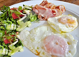 Fried eggs with fried bacon and a salad of fresh seasonal vegetables