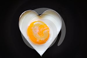 Fried eggs in a frying pan for breakfast on a black background Fried egg for a healthy heart and mind love cooking concept