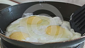 Fried eggs interfere with a spatula in a pan slowmotion