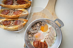Fried eggs in a pan with meat on the wooden plate. The famous breakfast with Banh Mi - Vietnamese bun with meat. Top-view
