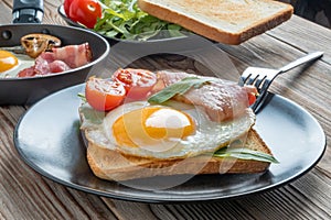 Fried eggs on plate and pan with fork, mushrooms and rukkola. Soft focus