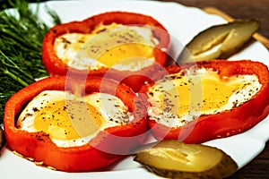 Fried eggs in red peppers on white plate