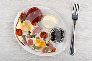 Fried eggs with sausages, tomato, ketchup, mayonnaise in bowls i