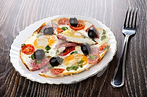 Fried eggs with sausages, tomato in plate, fork on table