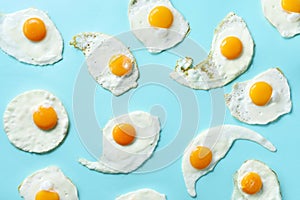 Fried eggs or scrambled eggs pattern on blue background. Creative food concept. Top view