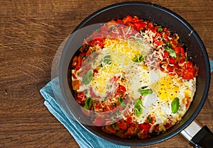 Fried eggs with vegetables and cheese in a frying pan