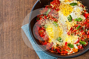 Fried eggs with vegetables and cheese in a frying pan