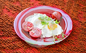 Fried eggs with vegetables on a red plate