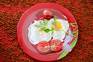 Fried eggs with vegetables on a red plate