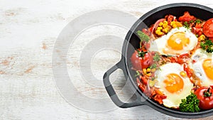 Fried eggs with vegetables: tomatoes, paprika, peppers, onions. Vegetable Shakshuka in a pan.