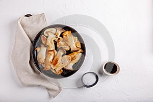 Fried eryngii mushrooms in cast-iron pan on white table. Grilled slices of king oyster mushrooms. Top view, copy space