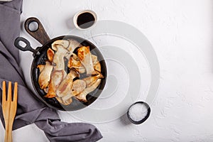 Fried eryngii mushrooms in cast-iron pan on white table. Grilled slices of king oyster mushrooms. Top view, copy space