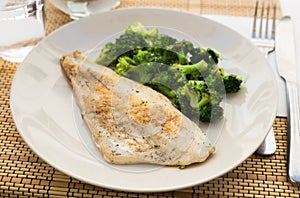 Fried fillet of sea bass with garnish of broccoli on black warm stone plate