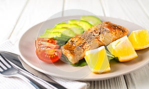 Fried fish with avocado, lemon, herbs and tomatoes on a platter