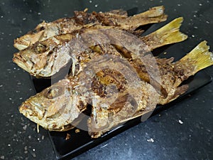 Fried fish on black plate and table backgrounds