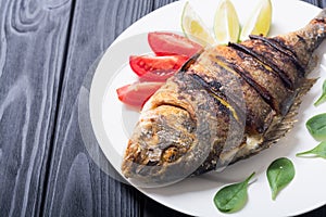 Fried fish dorado with lime , tomatoes and spinach