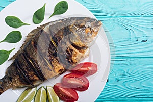 Fried fish dorado with lime , tomatoes and spinach . Sea food