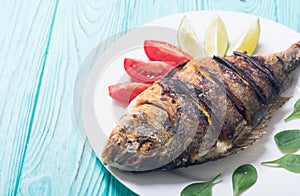 Fried fish dorado with lime , tomatoes and spinach