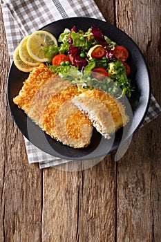 Fried fish fillet in breading and fresh vegetable salad close-up. Vertical top view