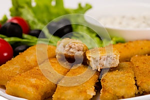 Fried fish fingers with vegetables close up