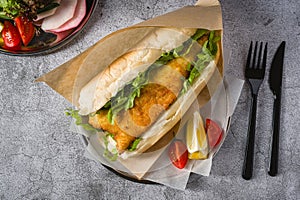 Fried fish sandwich with greens on the stone table. Turkish name Balik Ekmek