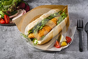 Fried fish sandwich with greens on the stone table. Turkish name Balik Ekmek