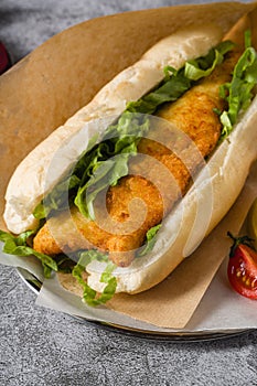 Fried fish sandwich with greens on the stone table. Turkish name Balik Ekmek