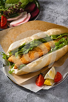 Fried fish sandwich with greens on the stone table. Turkish name Balik Ekmek