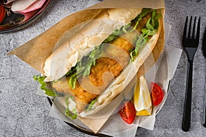 Fried fish sandwich with greens on the stone table. Turkish name Balik Ekmek