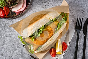 Fried fish sandwich with greens on the stone table. Turkish name Balik Ekmek