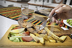 Fried fish served with french fries and salad with a hand sticking a fork on the plate